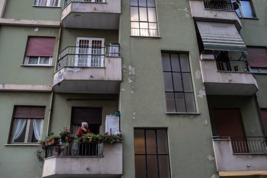 Seorang wanita melihat keluar dari balkonnya di lingkungan Prenestina di Roma. @npr.org/Nadia Shira Cohen