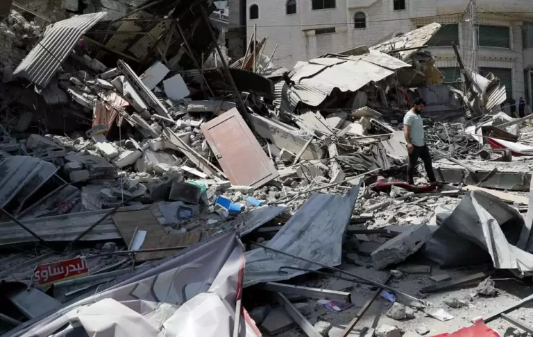 Seorang pria memeriksa puing puing bangunan pemukiman yang hancur akibat serangan udara Israel, di Kota Gaza, Kamis, 20 Mei 2021. (AP Photo / Adel Hana)
