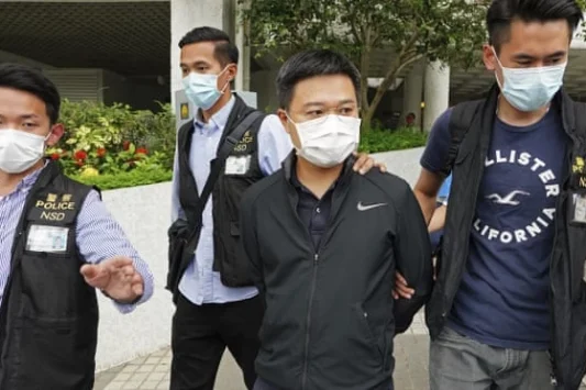 Polisi Hongkong membawa Pemimpin Redaksi Apple Daily Ryan Law dengan tangan terikat ke belakang. (Foto: AP)