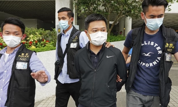 Polisi Hongkong membawa Pemimpin Redaksi Apple Daily Ryan Law dengan tangan terikat ke belakang. (Foto: AP)